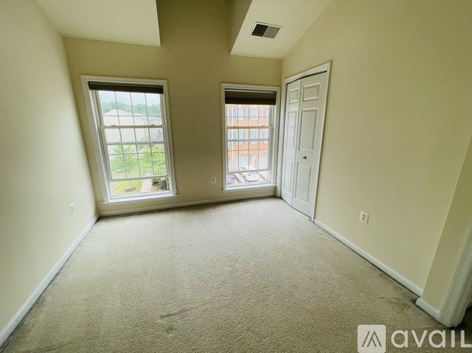 A room with a carpeted floor, two windows, and a door.