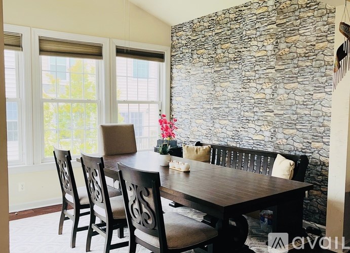 A dining room with a stone wall and a wooden table.