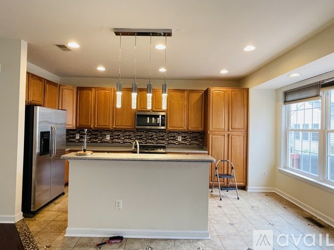 A kitchen with wooden cabinets and a stainless steel refrigerator.
