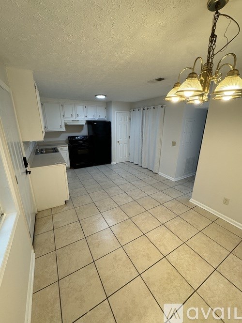 A kitchen with white cabinets and a black dishwasher.