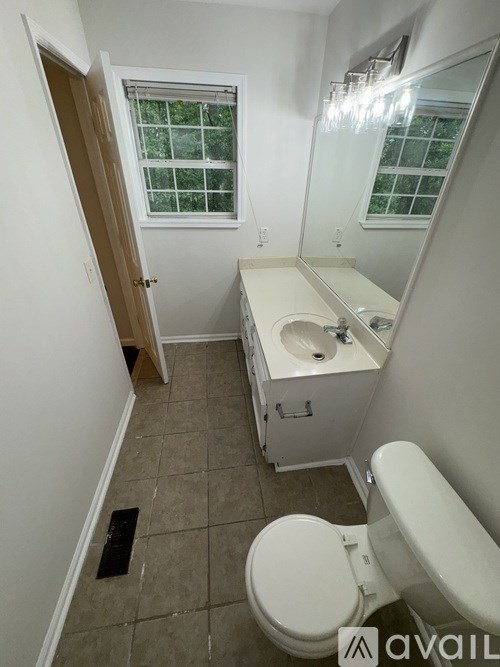 A bathroom with a toilet, sink, and mirror.
