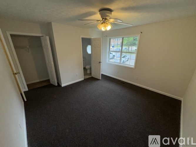 A room with a ceiling fan and a window with blinds.