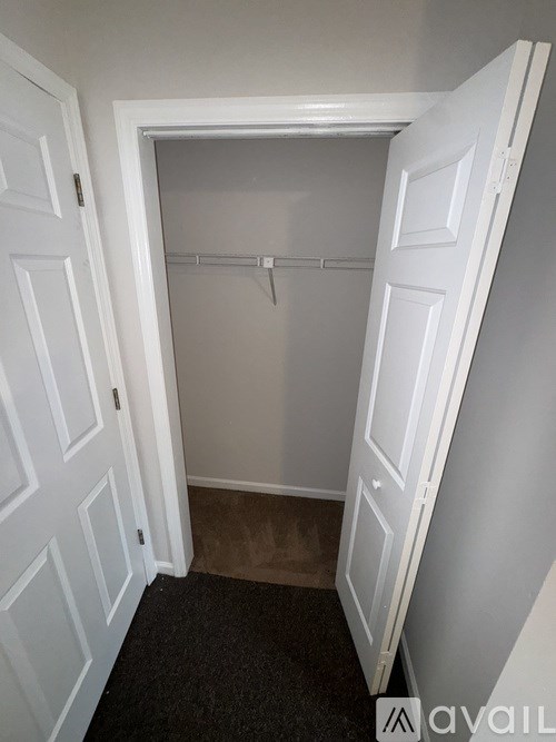 A white door is open to a small room with a carpeted floor.