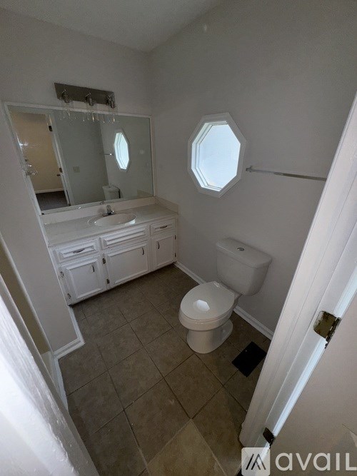 A bathroom with a toilet, sink, and mirror.