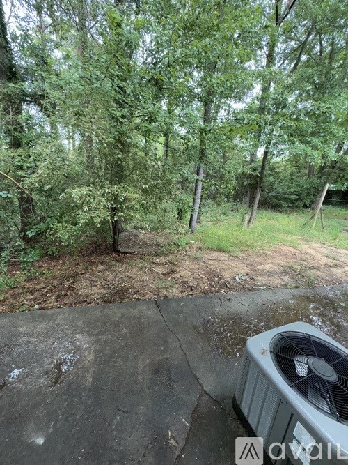 A fan is on a concrete surface surrounded by greenery.