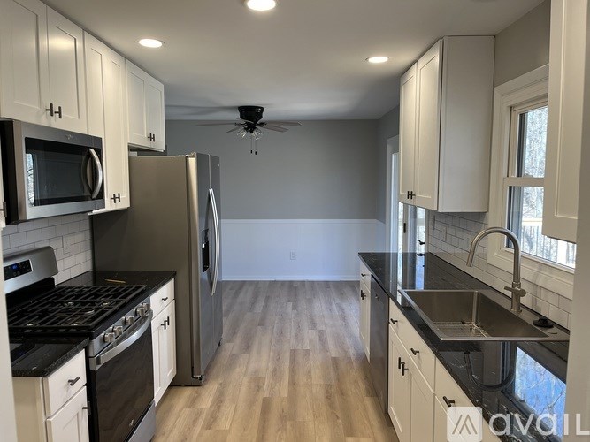 A kitchen with white cabinets and black countertops.