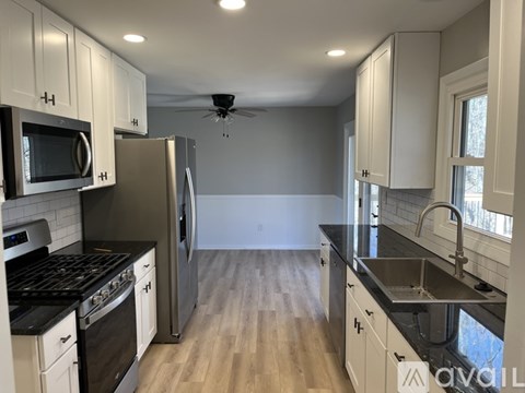 A kitchen with white cabinets and black countertops.