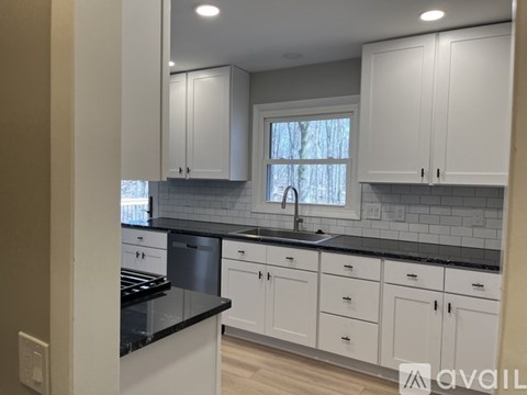 A kitchen with white cabinets and a black countertop.