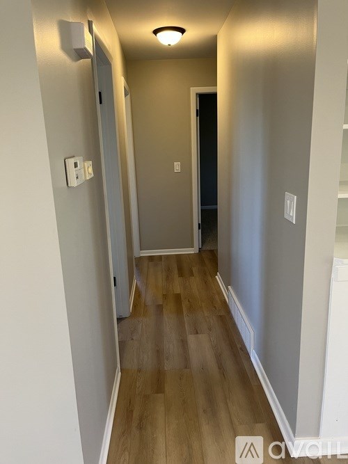 A hallway with wood floors and white walls.