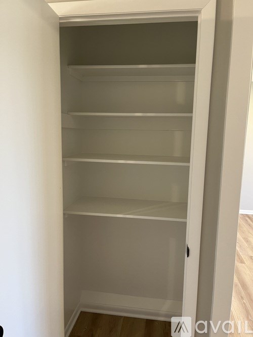 A white open pantry with shelves and a door.