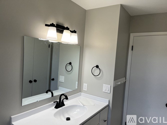 A bathroom with a sink, mirror, and light fixture.