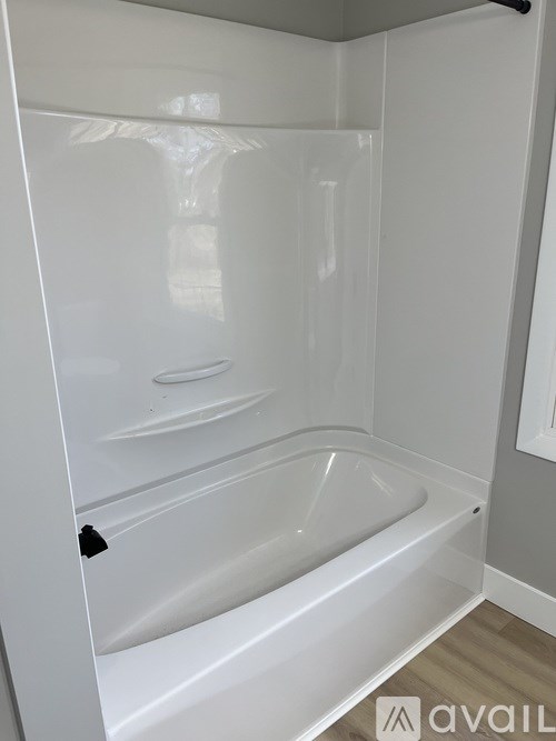 A white bathtub in a bathroom with a grey wall.