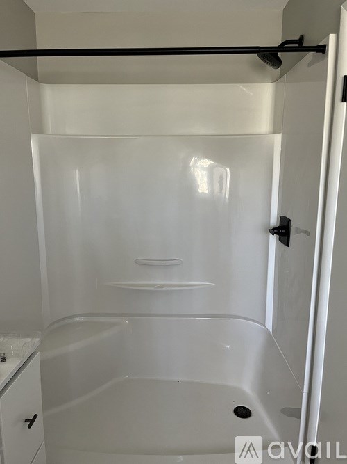 A white bathroom with a tub and a towel rack.