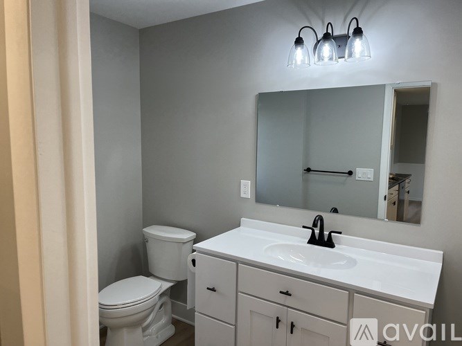 A bathroom with a toilet, sink, and mirror.