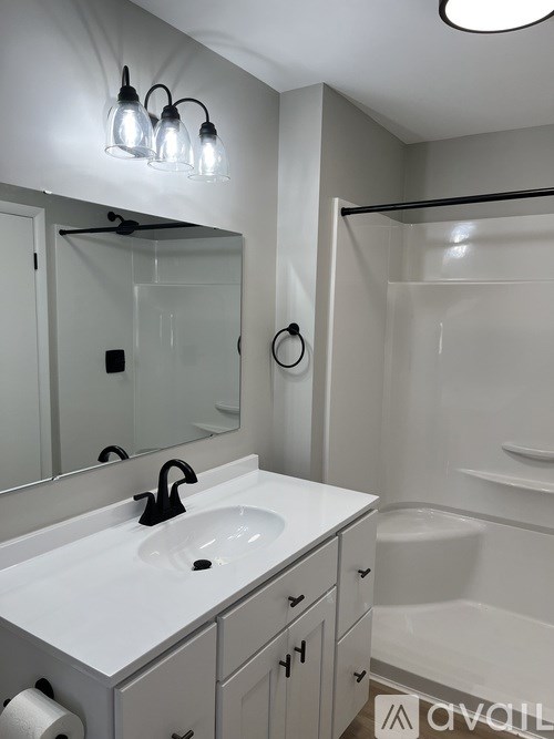 A white bathroom with a sink, mirror, and shower.