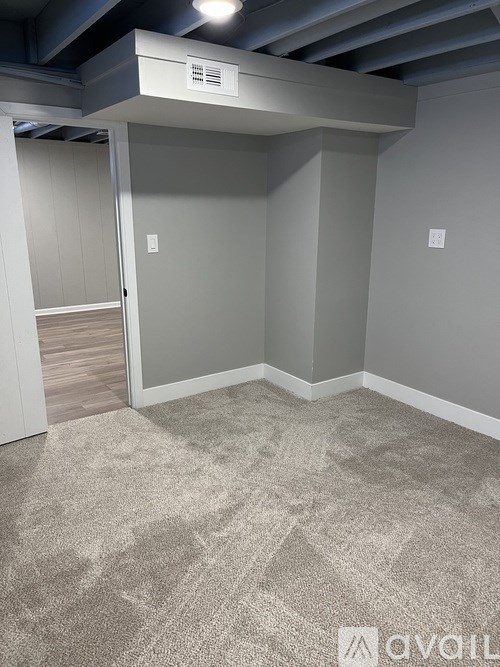 A room with a carpeted floor and a ceiling fan.