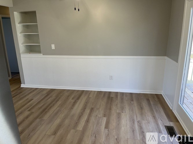 A room with wooden flooring and a white wall.