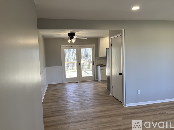 A spacious room with wooden flooring and a ceiling fan.