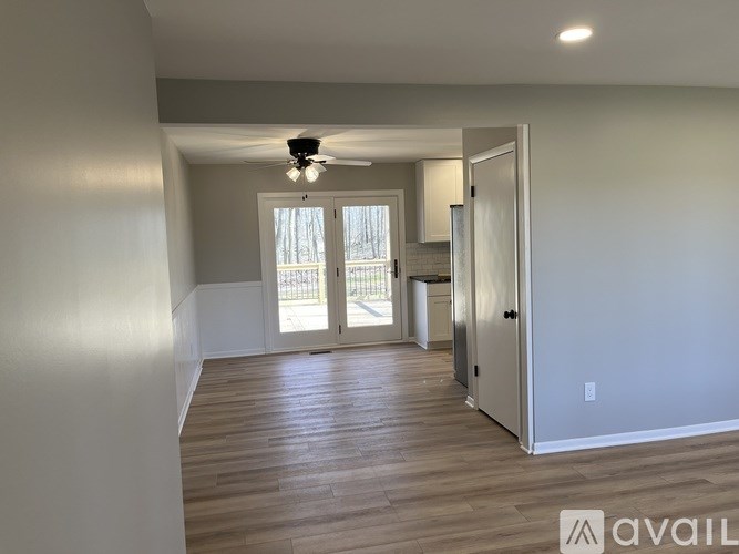 A spacious room with wooden flooring and a ceiling fan.