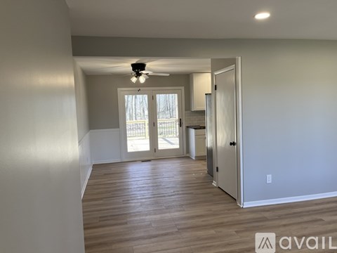 A spacious room with wooden flooring and a ceiling fan.
