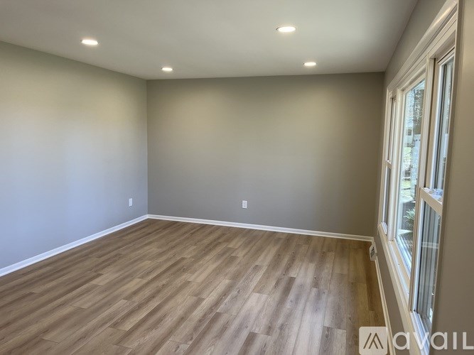 A room with wooden flooring and a window on the right side.