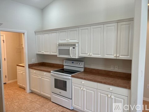 A kitchen with white cabinets and brown countertops.