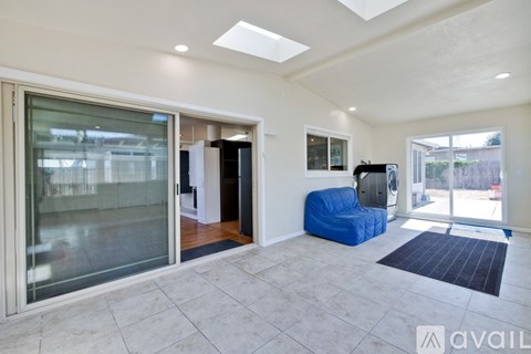 A spacious living room with a blue chair and a television.