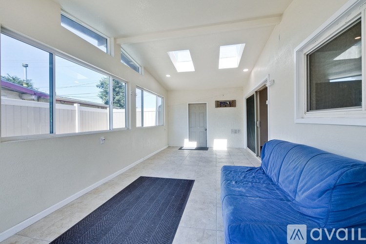 A blue couch is in a bright room with a rug on the floor.
