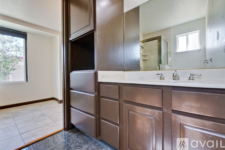 A bathroom with brown cabinets and a marble countertop.