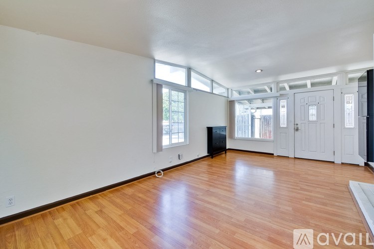 A spacious room with wooden flooring and a large window.