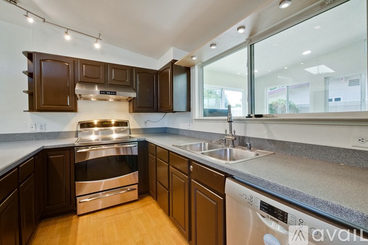 A kitchen with dark brown cabinets and a stainless steel oven.