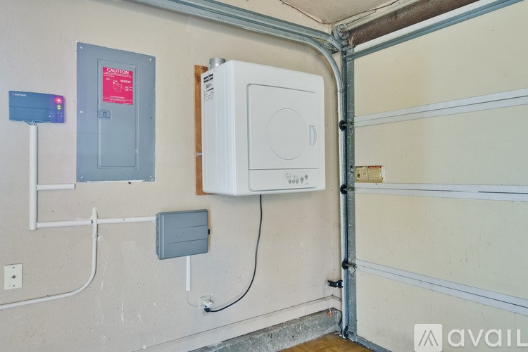 A wall-mounted electrical panel with a red label and a white box with a circular opening are mounted on a wall.