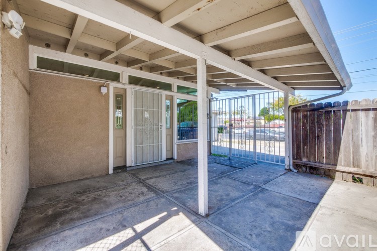 A patio area with a white roof and a glass door.