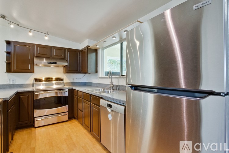 A kitchen with a stainless steel refrigerator and wooden cabinets.