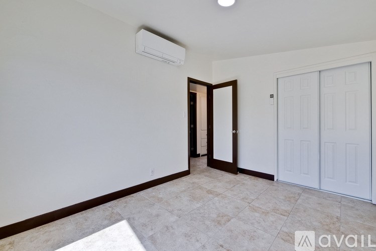 A room with a tiled floor and a white wall with a doorway leading to another room.
