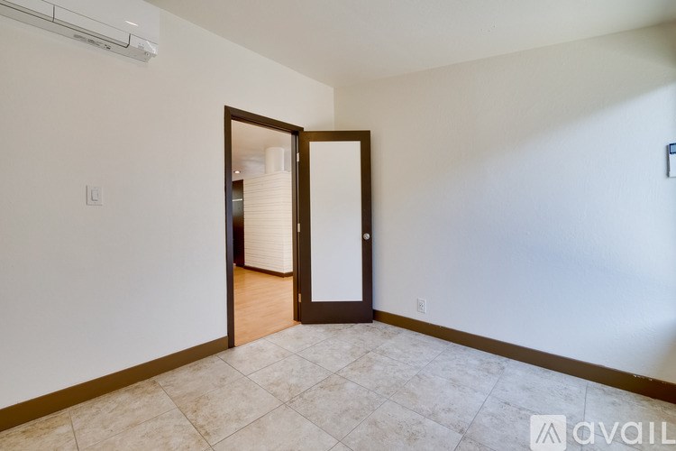 A room with a tiled floor and a door leading to another room.