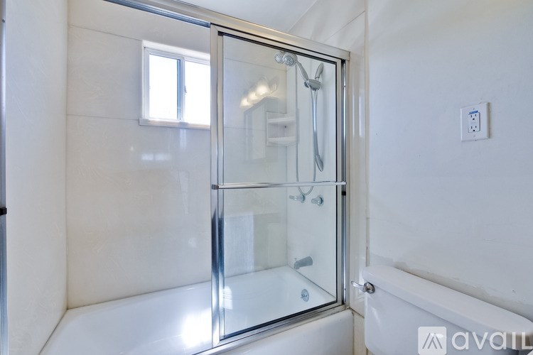 A white bathroom with a glass shower door and a white tub.