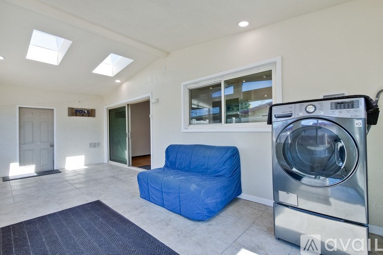 A washing machine is placed in a room with a blue sofa.