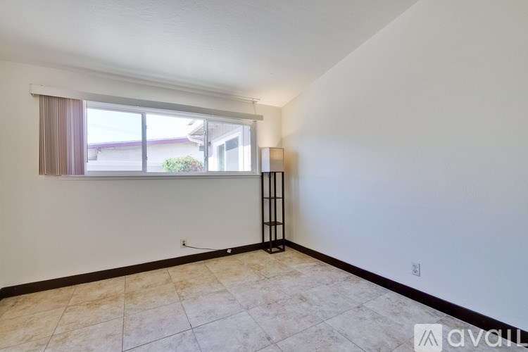 Empty room with a window and a lamp on the floor.
