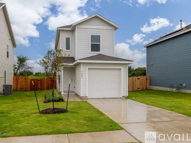 A house with a white garage door and a brown tree in the front yard.
