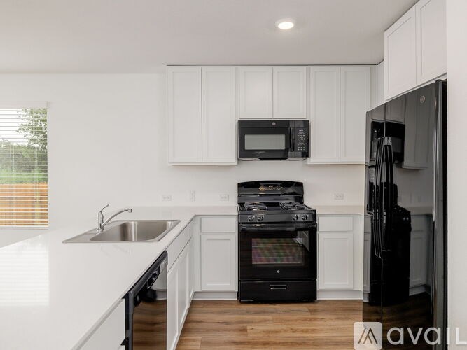 A kitchen with black appliances and white cabinets.