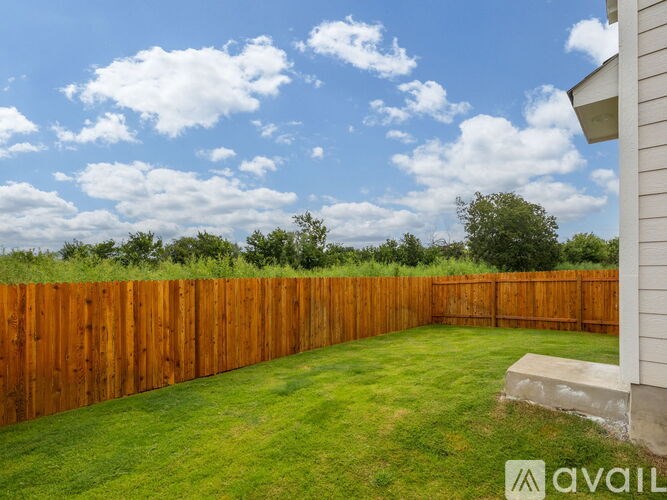 A backyard with a wooden fence and green grass.
