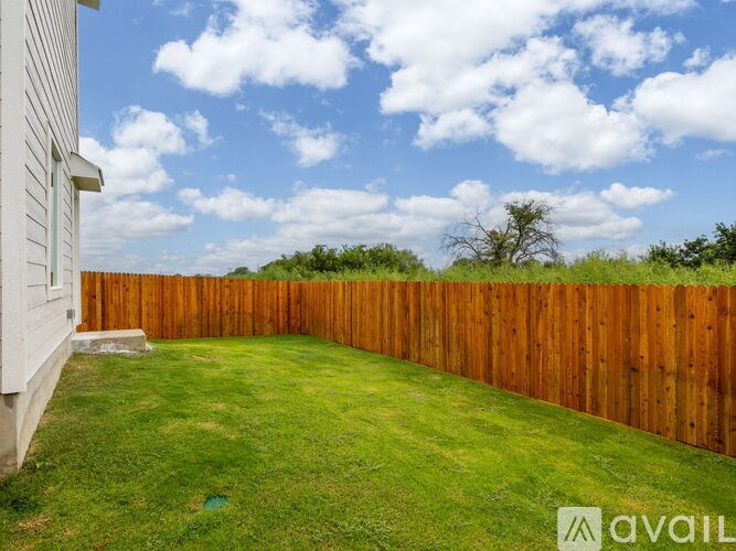 A backyard with a wooden fence and a house.