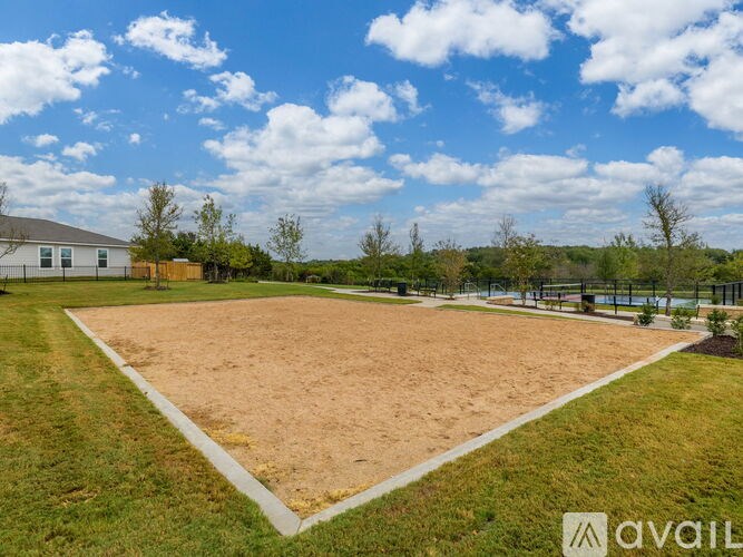 A large, empty sandy field with a building in the background.