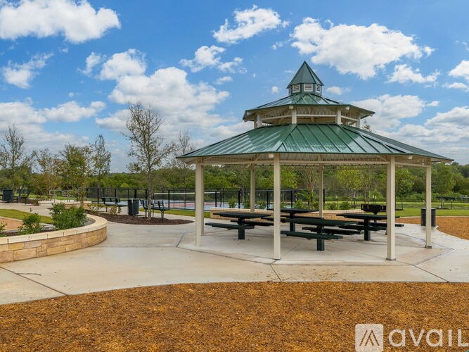 A gazebo with a green roof is surrounded by a circular walkway and benches.