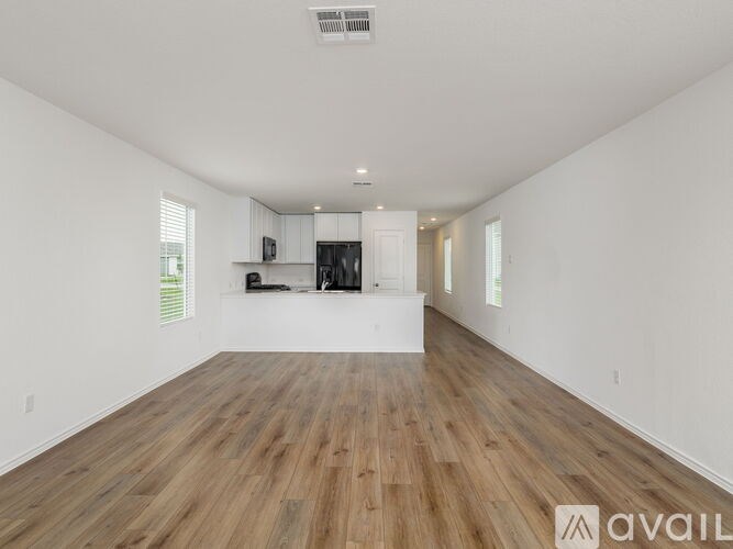 A spacious room with wooden flooring and white walls.