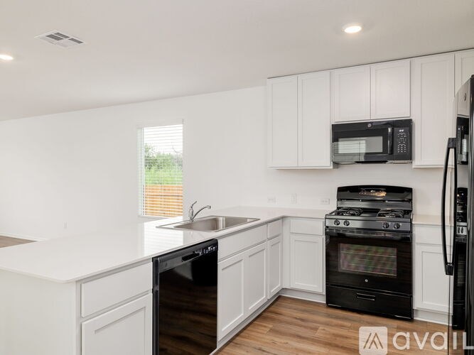 A kitchen with white cabinets and black appliances.