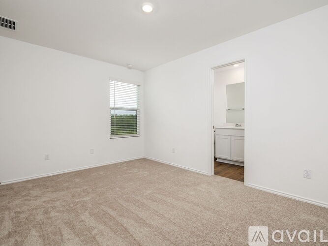 A spacious room with beige carpeting and a window with blinds.