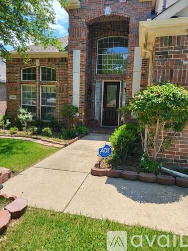 A brick house with a black door and a small garden in front.