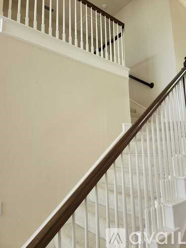 A staircase with white railings and a wooden handrail.
